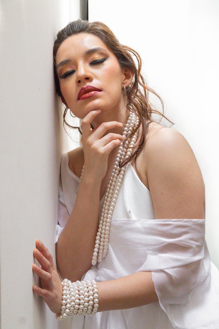 services-04 Stylish woman in white attire adorned with pearls, striking a dramatic pose.