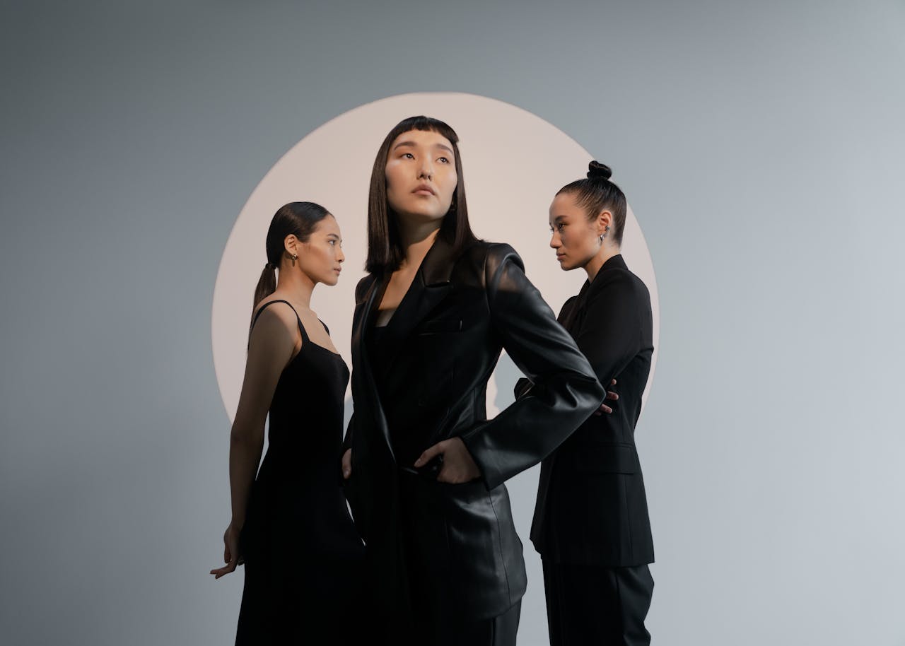 Group of Asian women in black outfits posing in a modern studio.